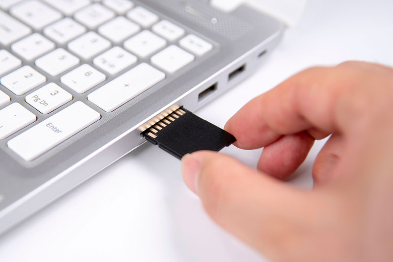 Personne qui insère une carte SD dans un ordinateur