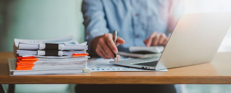 Professionnel qui utilise un ordinateur et rempli des documents