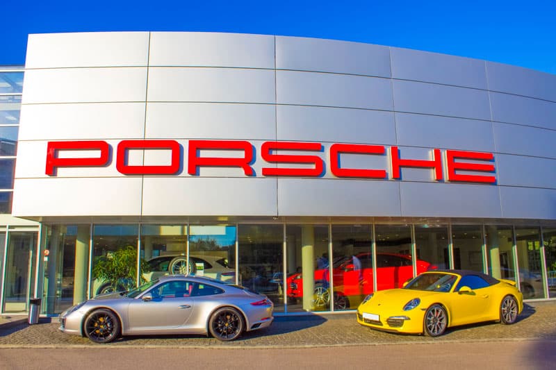 Zoom sur une concession Porsche avec des modèles stationnés devant