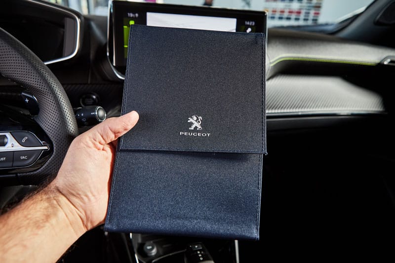 Zoom sur une personne qui tient un carnet d'entretien Peugeot