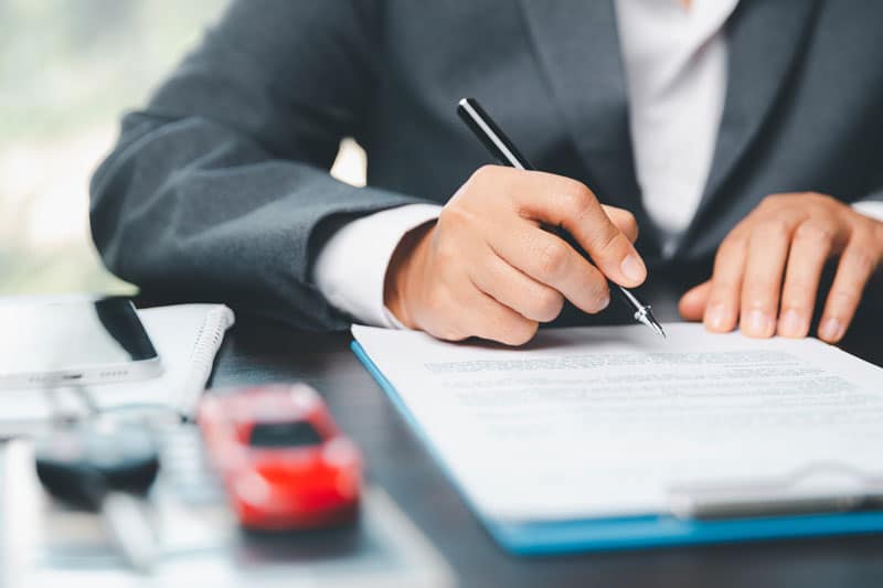 Zoom sur une personne qui signe un document pour acheter une voiture 