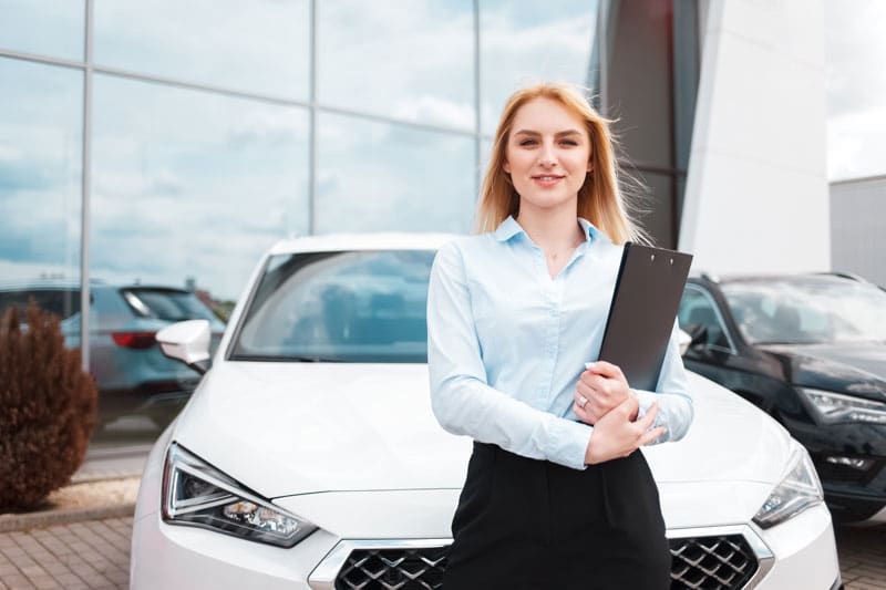 Mandataire automobile debout devant une voiture