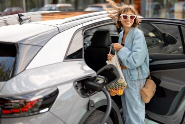 Une femme range ses courses dans sa voiture électrique qu’elle vient d'acheter grâce aux aides de l'État
